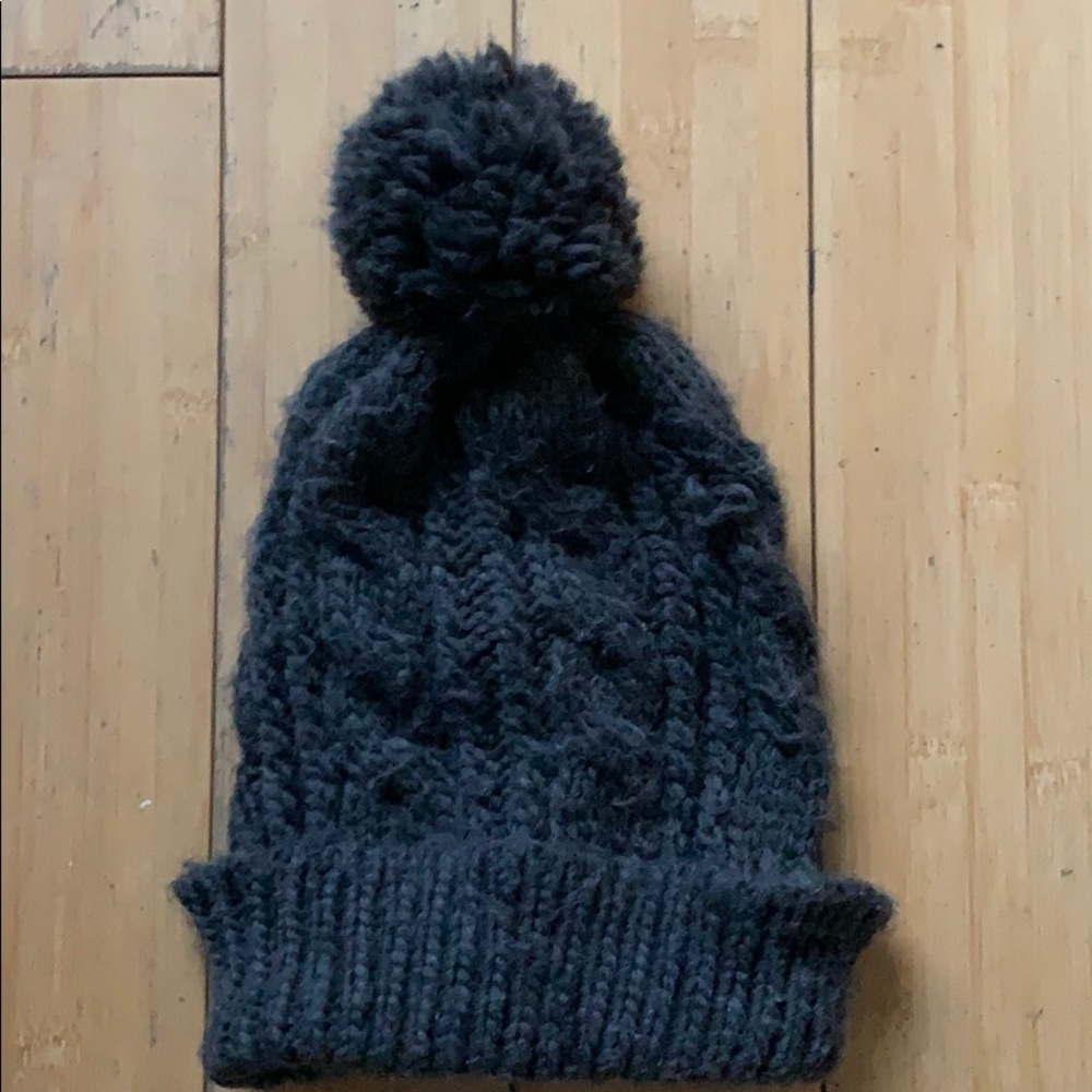 Dark gray winter knitted hat with puff ball.